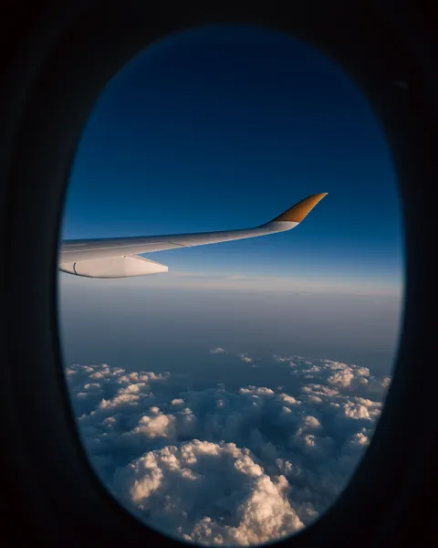 Blick aus dem Flugzeugfenster auf eine Tragfläche über Wolken